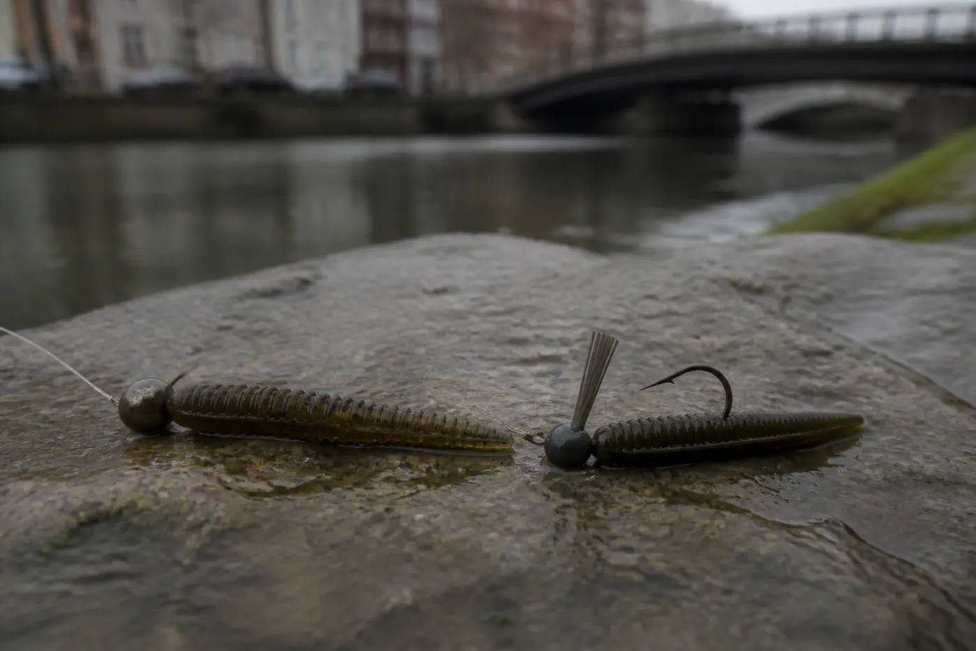 Ned-rig met mushroom jigkop en compact stickbait op natte stenen langs een Amsterdamse kade